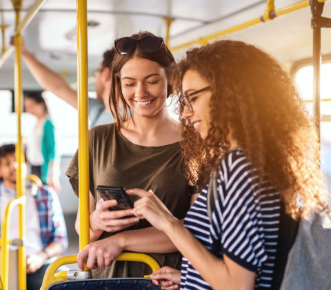 two people on bus using mobile phone